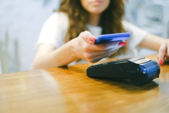 Mulher realiza um pagamento por aproximação com o celular em um terminal de pagamento.