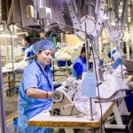 Trabalhadores operam máquinas de costura em uma fábrica têxtil.