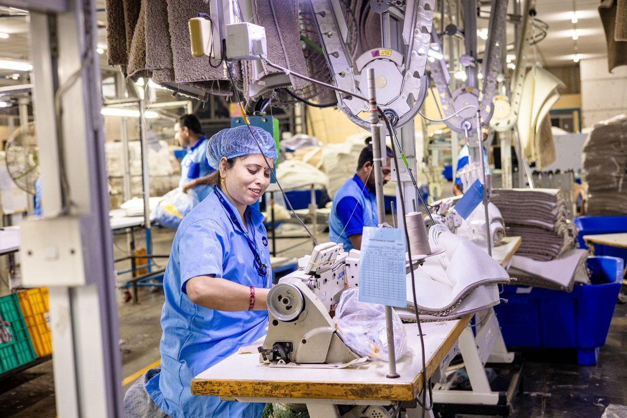 Trabalhadores operam máquinas de costura em uma fábrica têxtil.