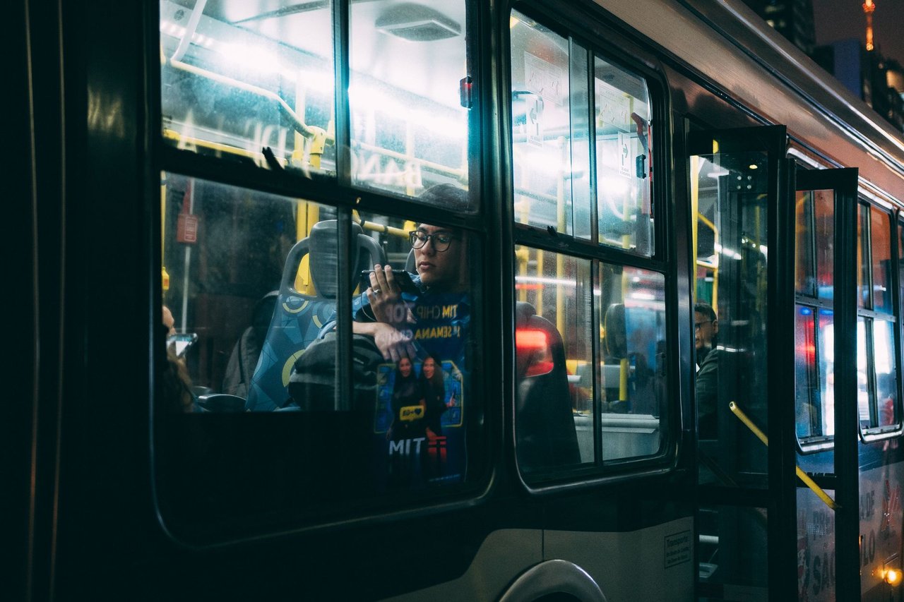 Passageiros viajam em um ônibus urbano à noite em São Paulo.
