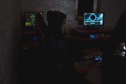 Profissional analisa dados em vários monitores em uma sala escura, em contexto de monitoramento de segurança cibernética.