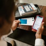 Pessoa confirma um pagamento digital usando um smartphone e um cartão em ambiente interno.