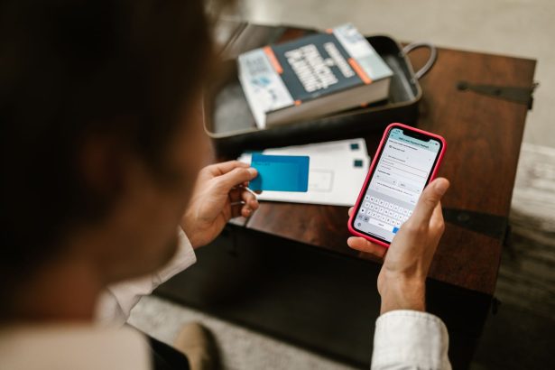 Pessoa confirma um pagamento digital usando um smartphone e um cartão em ambiente interno.