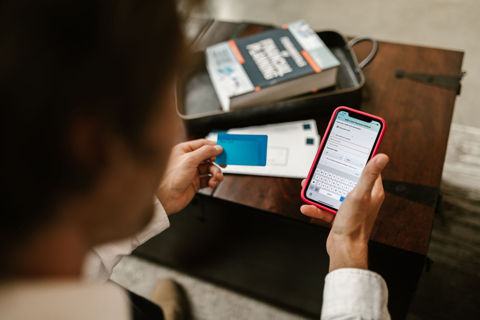 Pessoa confirma um pagamento digital usando um smartphone e um cartão em ambiente interno.