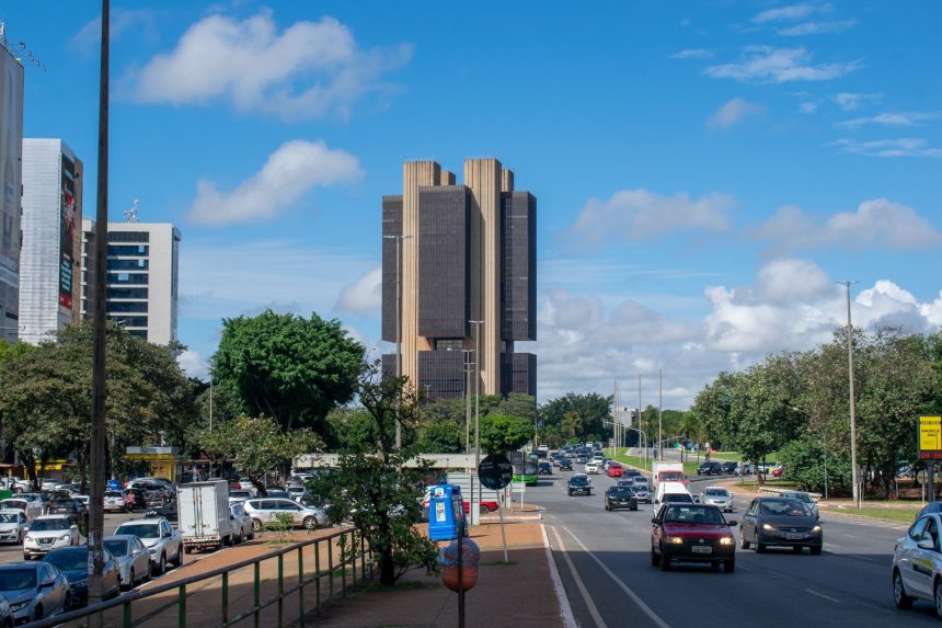 Vista externa do Banco Central do Brasil em Brasília sob um céu colorido.